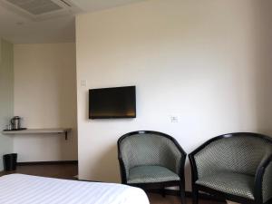 Cette chambre dispose de 2 chaises et d'une télévision murale. dans l'établissement Hotel Regal Malaysia, à George Town