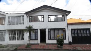 Casa blanca con puertas y ventanas negras en Hotel Palma de la Sabana, en Bogotá