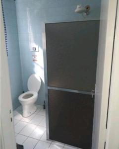 La salle de bains est pourvue de toilettes et d'une porte menant à une cabine de salle de bains. dans l'établissement Apto Temporada na Ilha de Paquetá, à Paqueta