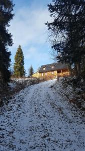 uma estrada coberta de neve que leva a uma casa em Bacówka w sercu gór - dom z bali w Gorcach em Łopuszna
