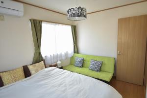 a bedroom with a bed and a green couch at near to Miyajima in Hatsukaichi