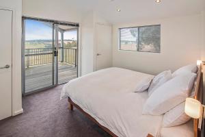 ein weißes Schlafzimmer mit einem großen Bett und einem Balkon in der Unterkunft Margaret River Farmhouse in Rosa Glen