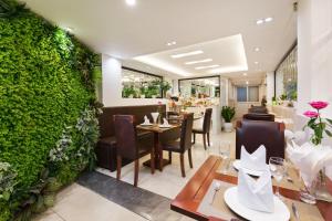 a restaurant with tables and chairs and a green wall at Splendid Pearlight Hanoi in Hanoi