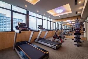 a gym with treadmill and ellipticals in a room with windows at Nesta Hotel Hanoi in Hanoi
