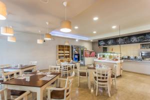 a restaurant with tables and chairs and a kitchen at Silver Bay Hotel Kontokali Corfu in Kontokali