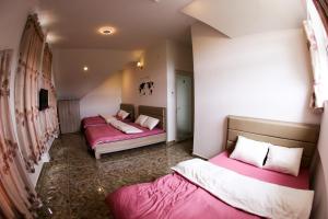 SAKURA HOMESTAY في Manline: سريرين في غرفة صغيرة مع ملاءات وردية