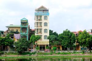 a tall white building next to a river at Xuan Hoa Hotel in Ninh Binh