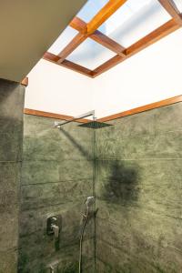a bathroom with a glass shower with a ceiling at The Ayur Villa in Kovalam