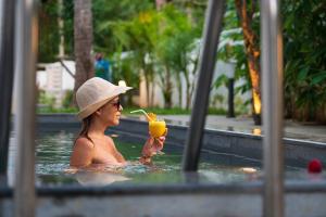 a woman in a swimming pool drinking a drink at The Ayur Villa in Kovalam