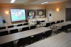 a classroom with tables and chairs and a projection screen at Vila DeLux in Negotin