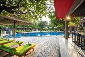 a swimming pool with green chairs and an umbrella at Kuta Seaview Boutique Resort in Kuta