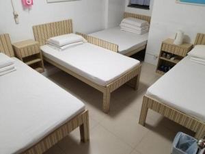 a room with three beds with white sheets and chairs at Asia Travel House in Hong Kong