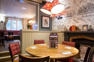 a restaurant with a wooden table and chairs and a fireplace at Toby Carvery Beckenham by Innkeeper's Collection in Bromley