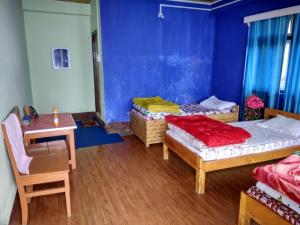 um quarto com três camas e uma mesa e cadeiras em Vamoose Red Panda em Sombāri