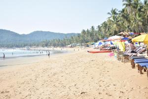 a beach with chairs and umbrellas and people on it at Club Palolem Resort in Palolem