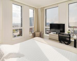 a bedroom with a bed and a tv and windows at H10 London Waterloo in London