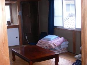 高槻市にあるハウス オブ ザ ライジング サンのテーブルとベッド、窓が備わる客室です。