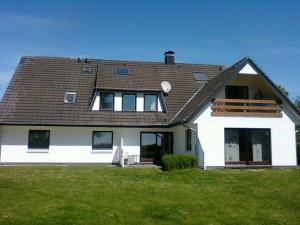 a white house with a roof on a green field at Haus-Halligblick-Ferienwohnung-Hamburger-Hallig in Dagebüll