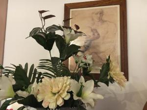 un jarrón lleno de flores blancas delante de un cuadro en New Maria's House Livorno. Il Cisternone en Livorno