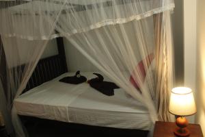 two ducks sitting on a bed with curtains at Sujee Villa in Unawatuna