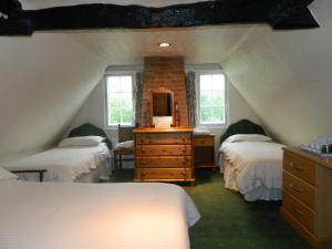 a attic bedroom with two beds and a dresser with a mirror at The Cedars Hotel in Stowmarket