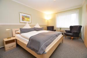 a hotel room with a large bed and two chairs at Hotel-Pension Anjo in Büsum