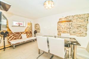 a dining room with a stone wall and a glass table and chairs at Apartments Salčinović in Medulin