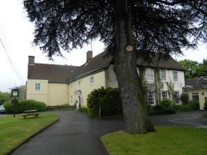 uma casa com uma árvore em frente em The Cedars Hotel em Stowmarket