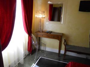 a room with a table and a mirror and red curtains at Locanda Villa Moderna in Genoa