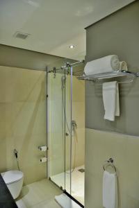 La salle de bains est pourvue d'une douche en verre et de toilettes. dans l'établissement EPIC Hotel & Suites, à Nyagatare