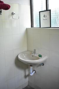 La salle de bains blanche est pourvue d'un lavabo et d'un miroir. dans l'établissement Club Palolem Resort, à Palolem