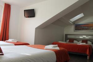 a hotel room with two beds and a tv at Hôtel du Centre in Soustons