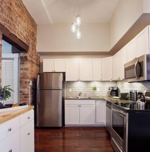 La cuisine est équipée de placards blancs et d'un réfrigérateur en acier inoxydable. dans l'établissement 416A Waldburg st · Newly Renovated 1920's Historic District Apt, à Savannah