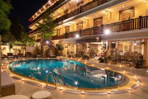 a swimming pool in front of a building at night at At Chiang Mai - SHA Extra Plus in Chiang Mai