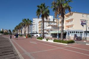 une rue de la ville avec des palmiers et des bâtiments dans l'établissement Alquileres Figuerola Los Abanicos, à Peñíscola