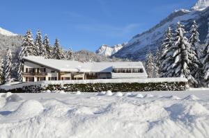 ein Haus voller Schnee in den Bergen in der Unterkunft Hôtel Les Sources in Les Diablerets