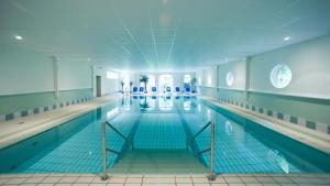 a large swimming pool with blue chairs in it at Hotel Aselager Mühle in Herzlake