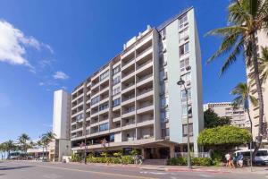 un gran edificio blanco en una calle con palmeras en @ Marbella Lane Studio, 15 steps from the Beach, 11 mins from the Airport en Honolulu