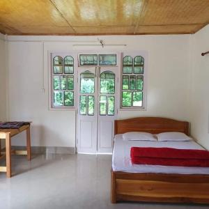 um quarto com uma cama e algumas janelas em Vamoose Orange Valley Sittong em Karsiyang