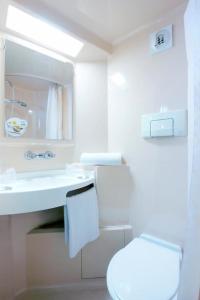 La salle de bains blanche est pourvue de toilettes et d'un lavabo. dans l'établissement Première Classe Valence Sud, à Valence