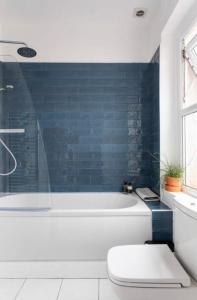 uma casa de banho com uma banheira branca e uma parede de azulejos azuis em Beautiful Two Bed Mumbles Flat - with parking space em The Mumbles