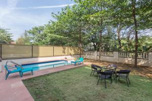 a swimming pool in a yard with chairs and a table at StayVista's Greenwoods Villa 5 - City-Center Villa with Private Pool, Terrace, Lift & Music System in Lonavala