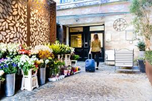 una donna che entra in un negozio di fiori con una valigia di The Alma Hotel a Londra