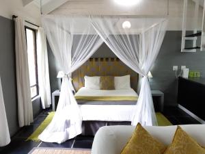 a bedroom with a canopy bed with white curtains at Hornbill House Self Catering Accommodation in Hermanus