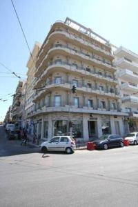 une voiture blanche garée devant un grand bâtiment dans l'établissement Ariston Hotel, à Athènes