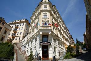 a tall white building with a clock tower on it at Spa Hotel Schlosspark in Karlovy Vary