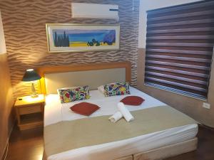 Habitación pequeña con cama con almohadas rojas en City Suites, en Eilat