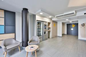 a waiting room with chairs and a table and a refrigerator at B&B HOTEL Montélimar Nord in Les Tourrettes