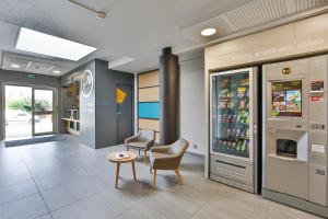 una sala de espera con un enfriador de bebidas en una tienda en B&B HOTEL Montélimar Nord, en Les Tourrettes