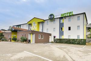 un hotel con un estacionamiento delante de él en B&B HOTEL Montélimar Nord, en Les Tourrettes